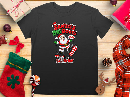 Black t-shirt with cartoon Santa and text "Santa's Big Boots, Tiny Steps, Big Ho-Ho!".